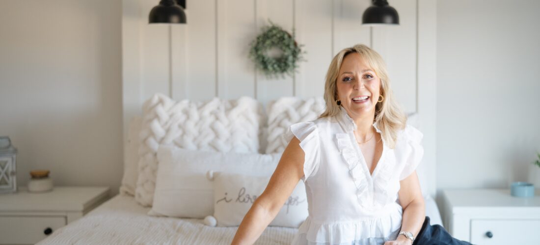 a realtor takes branding photos she is wearing a white top and is smiling at the camera in a room