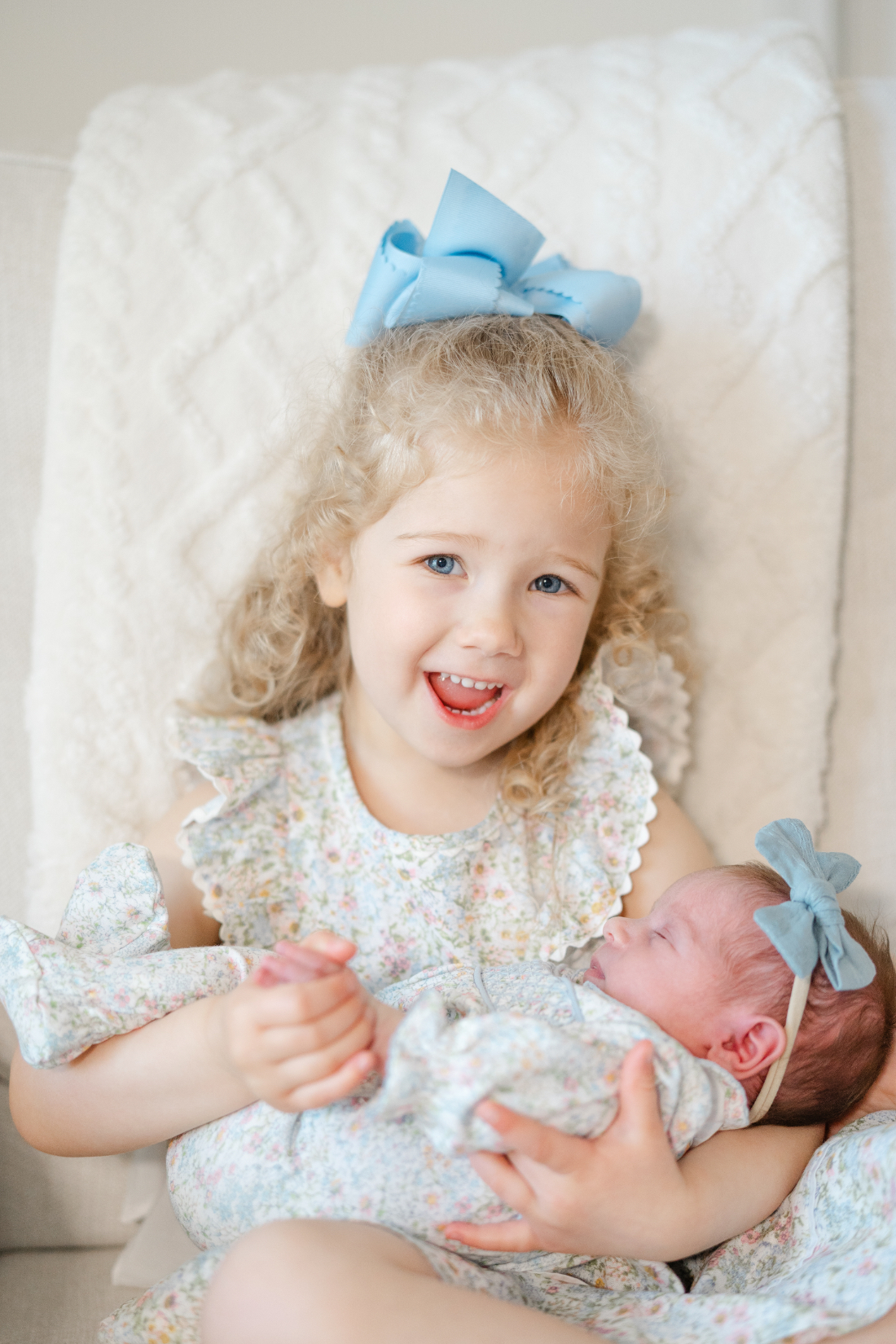 Big sister wearing blue bows holding newborn during Franklin newborn photography session