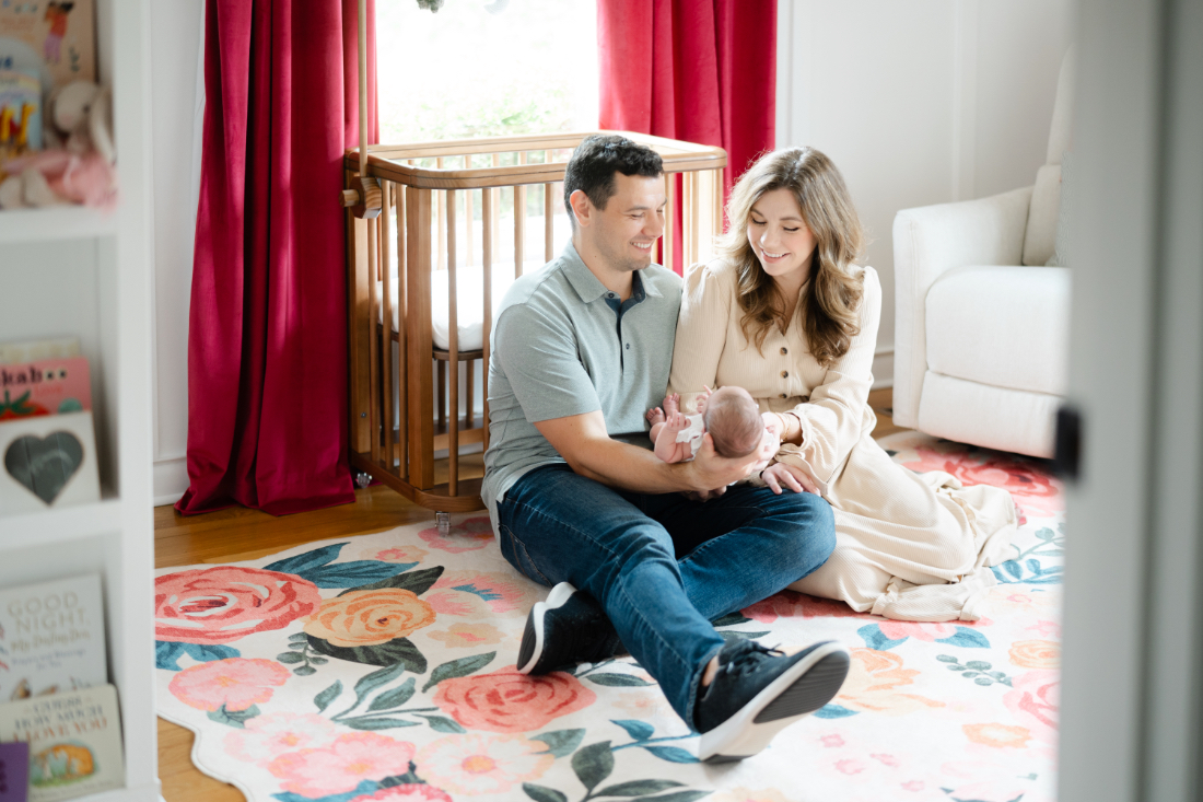 Parents sitting on nursery floor holding their newborn during Franklin newborn photography session