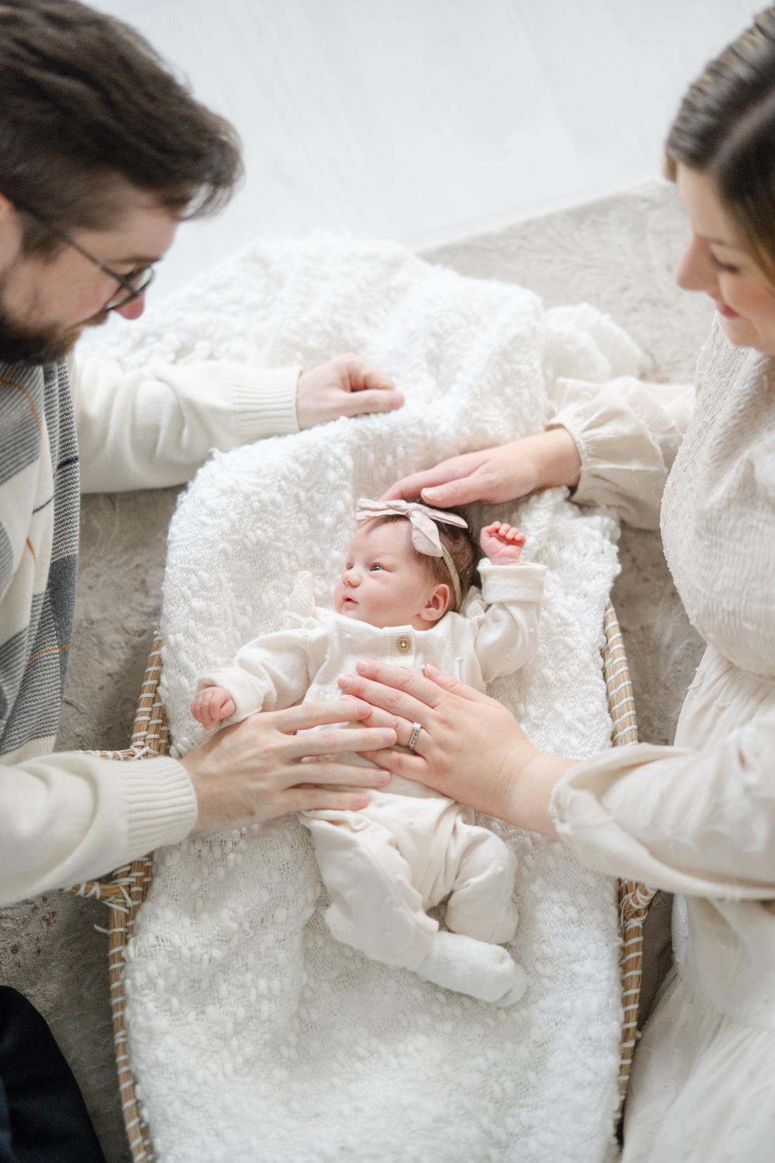 Natural newborn photo session moment with baby laying in a woven basket and parents nearby