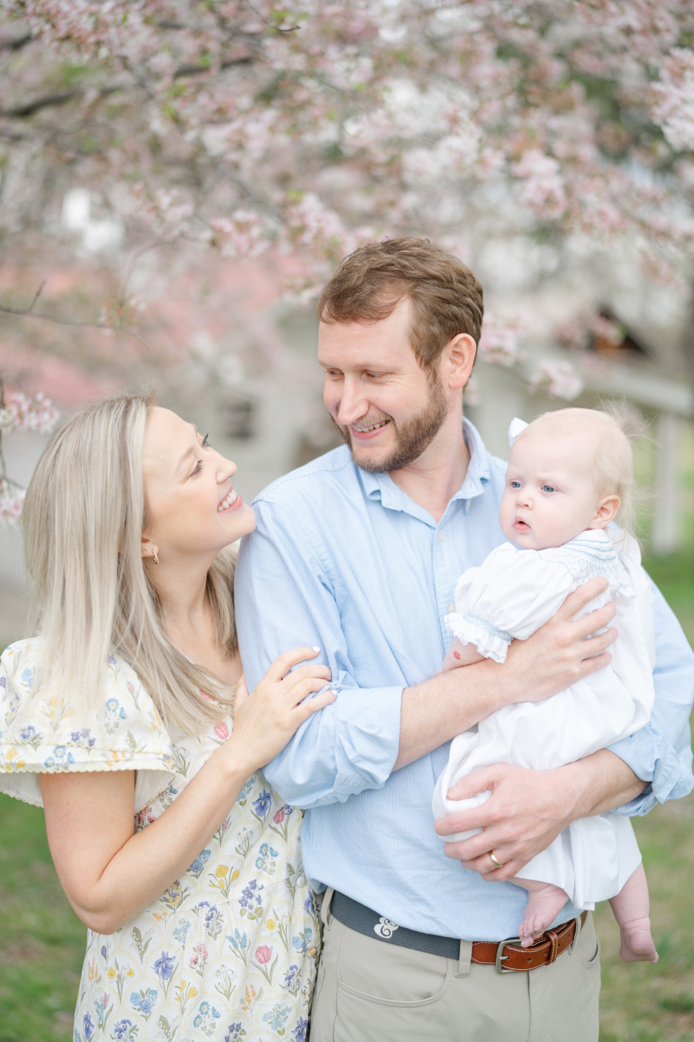 Parents holding their baby under blooming trees during a spring family photography session 