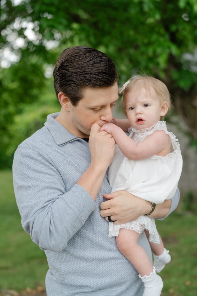 Dad kissing his daughter's hand during a spring family photo session at Ravenswood Mansion in Nashville TN