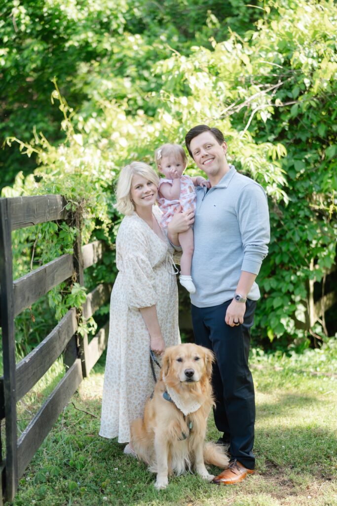 Family with their dog by the fence line during a spring family photo session at Ravenswood Mansion in Nashville TN
