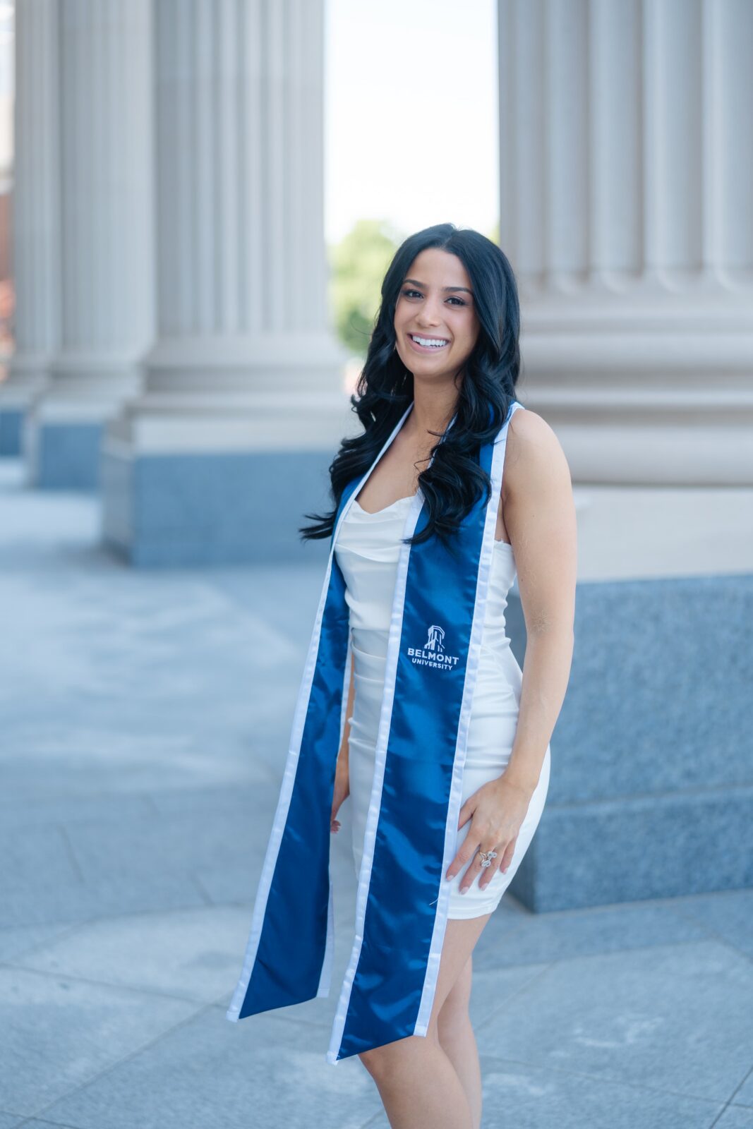 Nashville college graduation portrait at Belmont University Fisher Center with graduate in white dress and blue stole