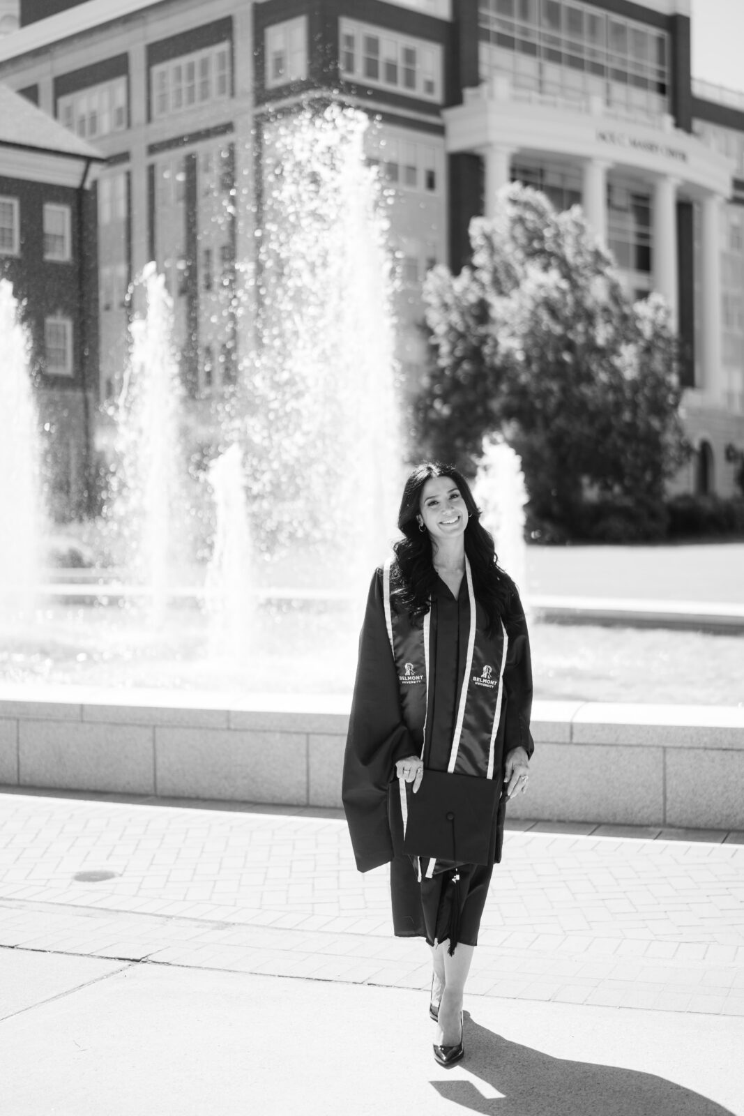 Black and white Belmont University graduation portrait with a grad in cap and gown near the campus fountain in Nashville TN