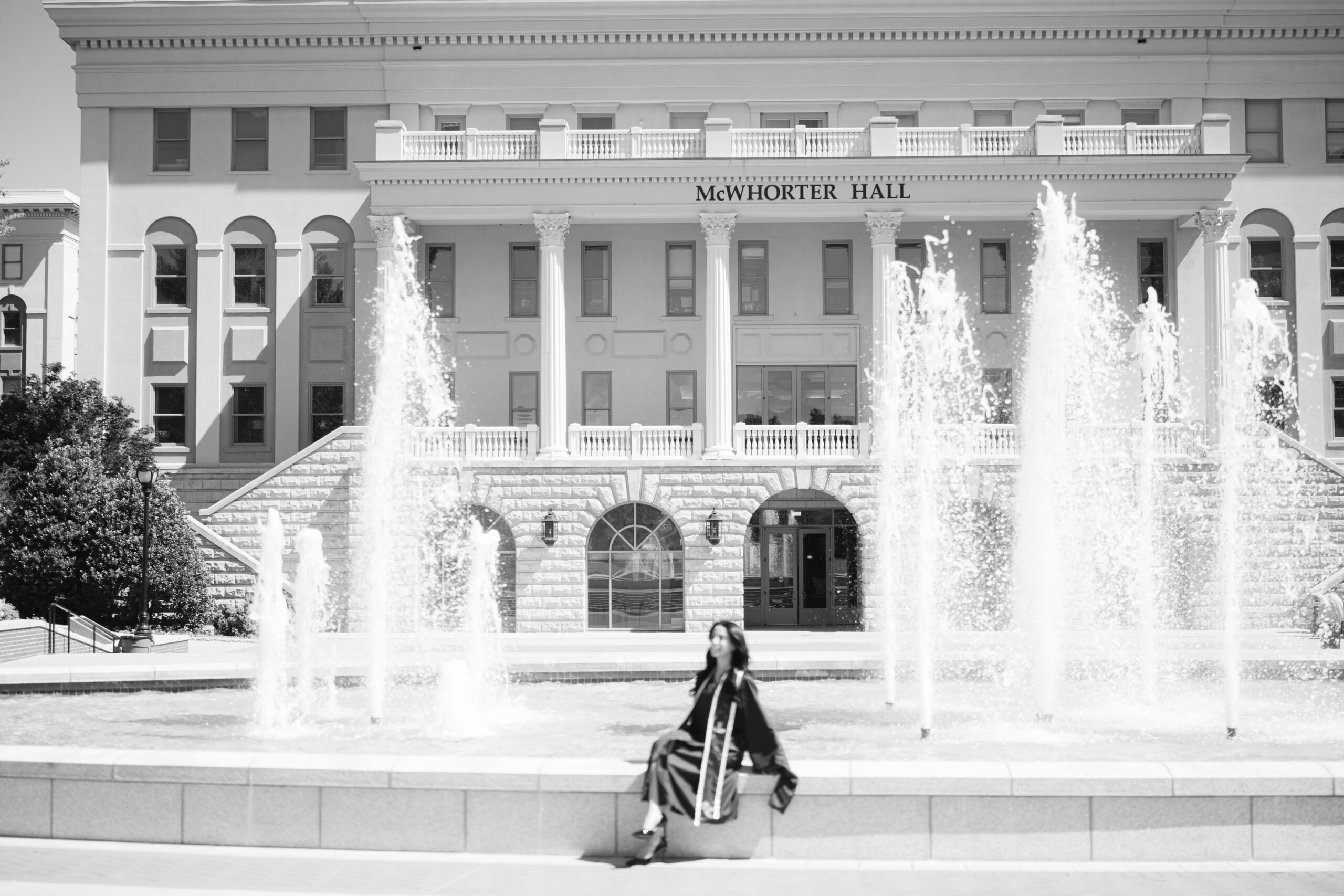 Wide angle black and white graduation photo at Belmont University showing McWhorter Hall and the campus fountain in Nashville