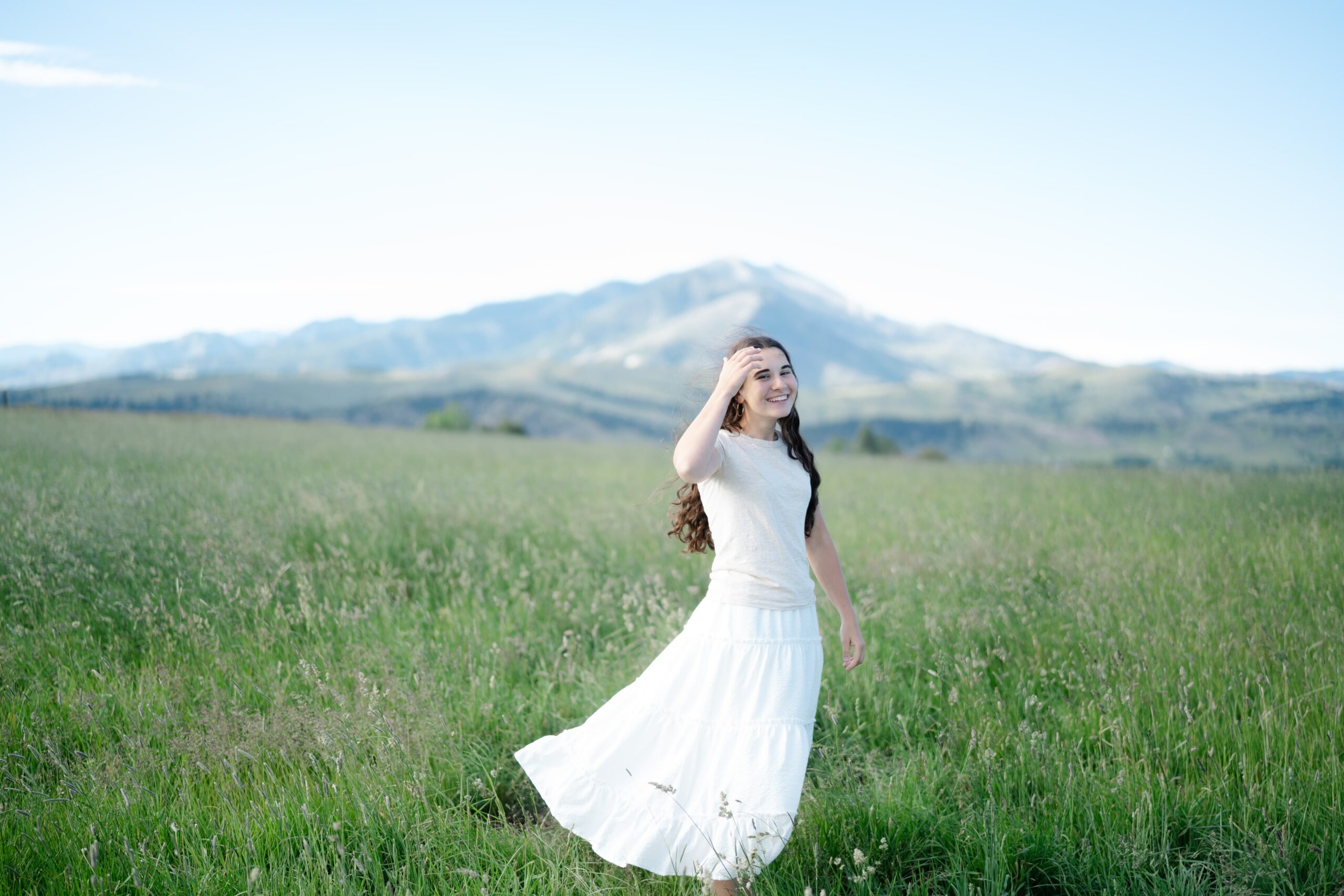 Bozeman Montana senior photographer captures a senior twirling in a mountain meadow near the Bridger Mountain Range.