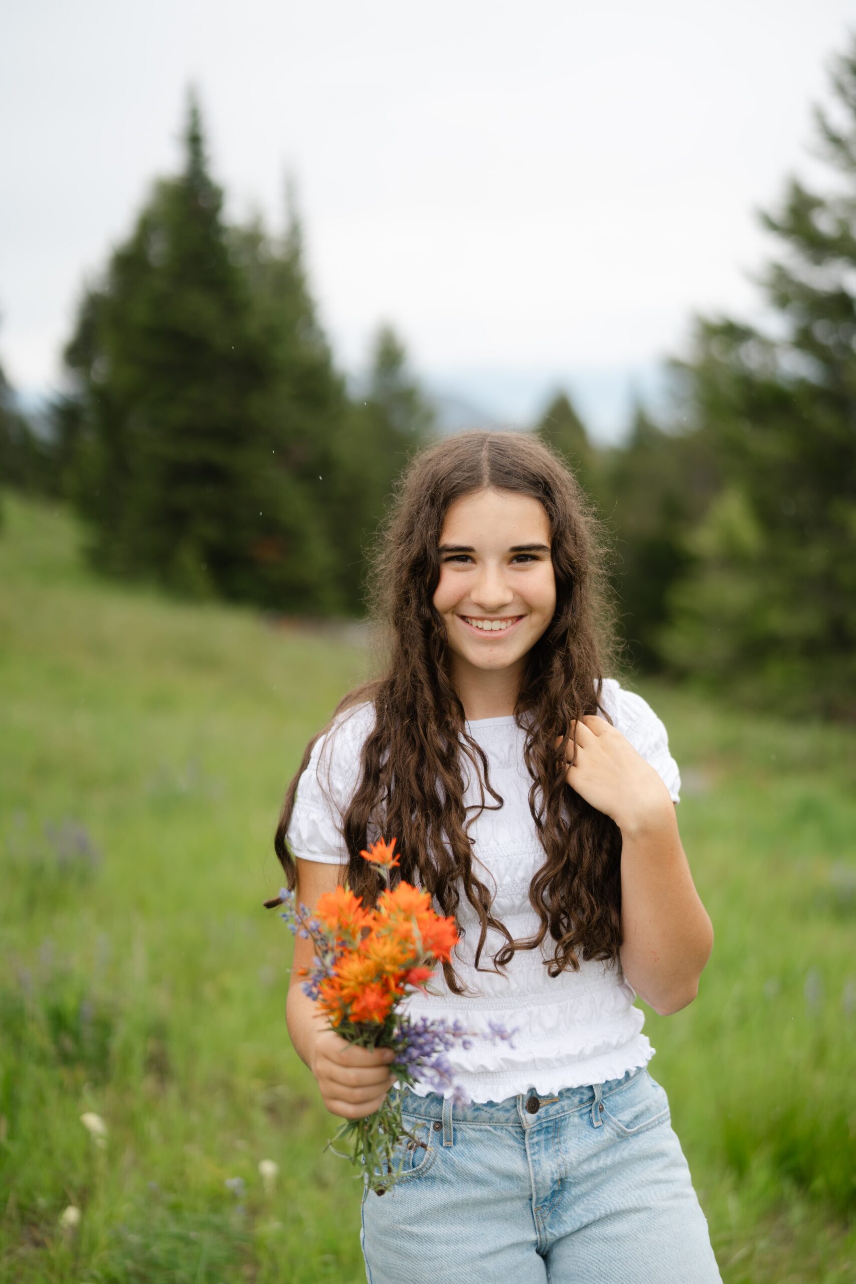 A senior portrait featuring wild Indian paintbrush and lupine picked during a Montana hiking session.