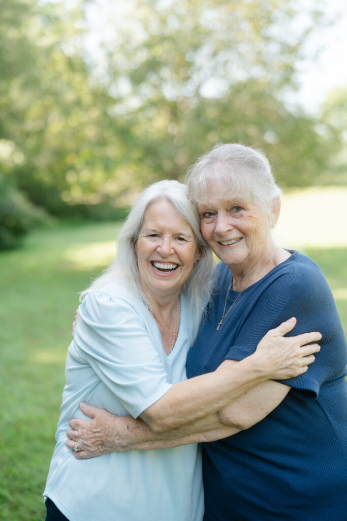 Two grandmothers sharing a joyful hug during a multigenerational family photography session.