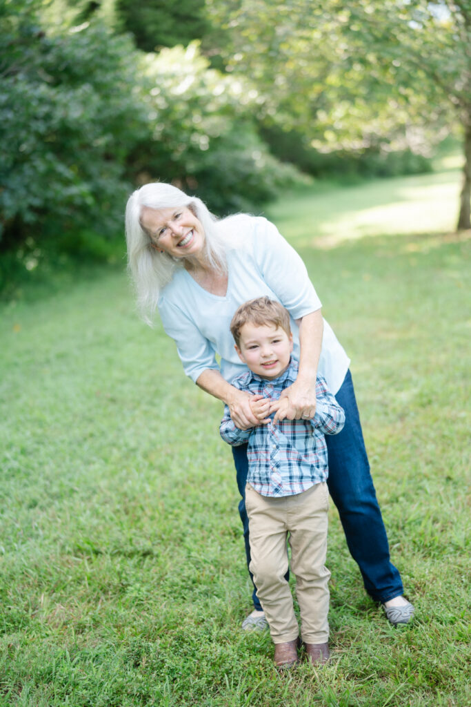 Grandmother holding hands with her young grandson during an outdoor family portrait session.