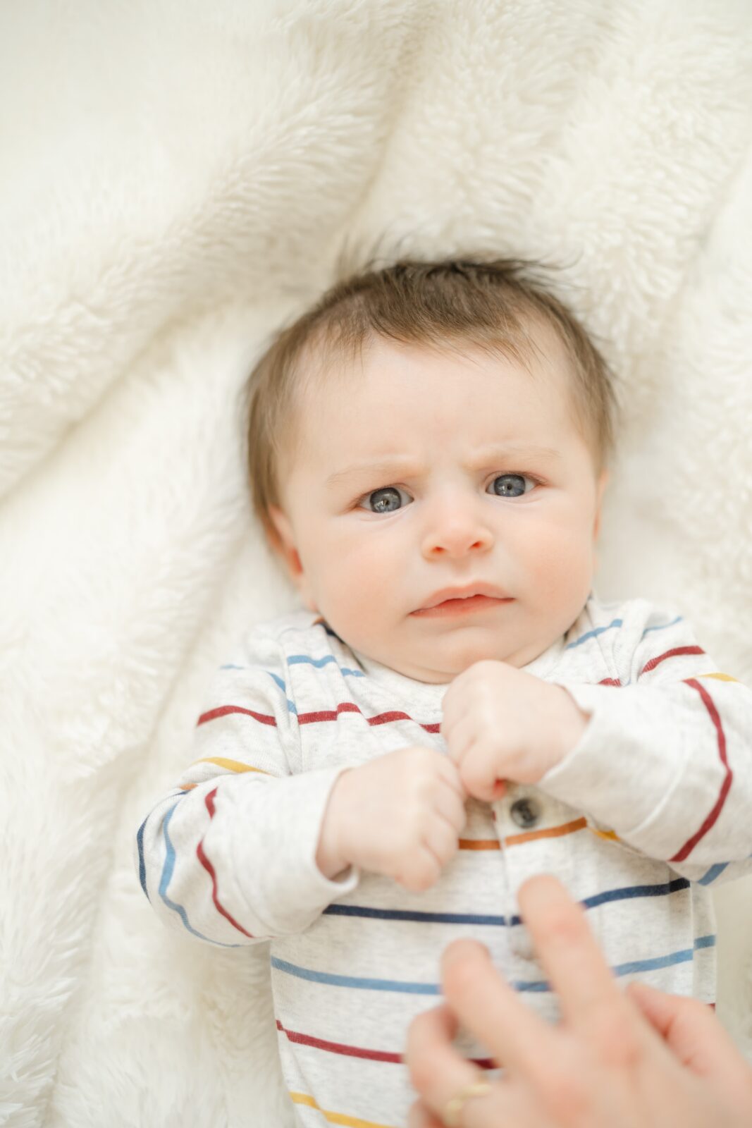 Baby boy on a cozy white blanket during an at home family photography session in Nashville TN