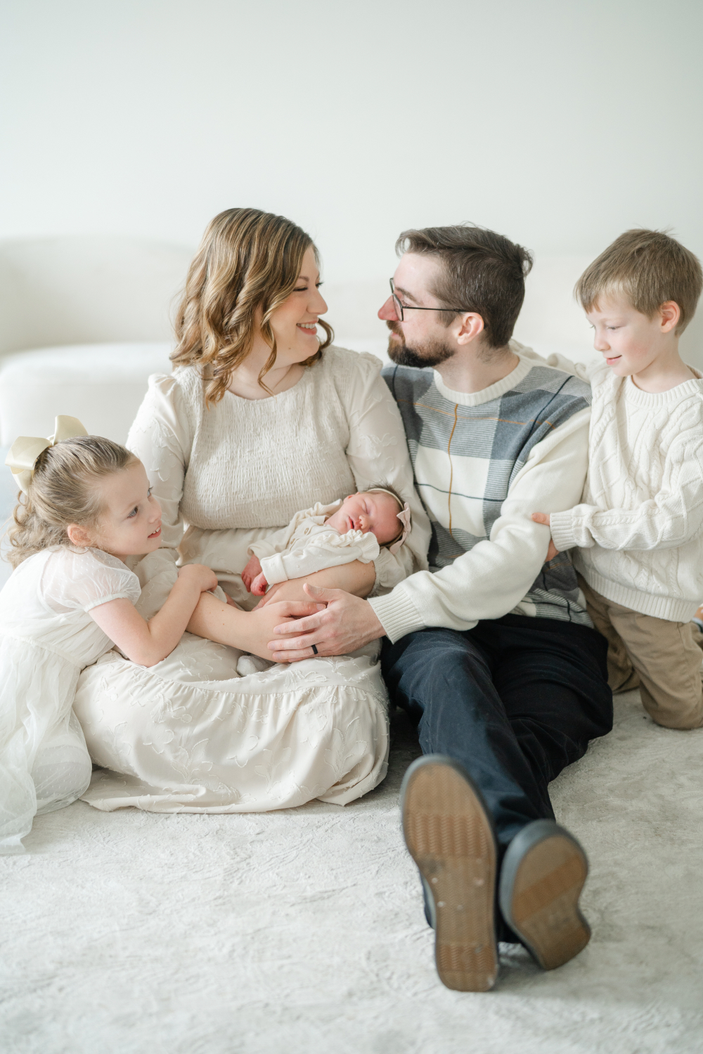 Parents sitting with their newborn son and two older siblings for a lifestyle family portrait.