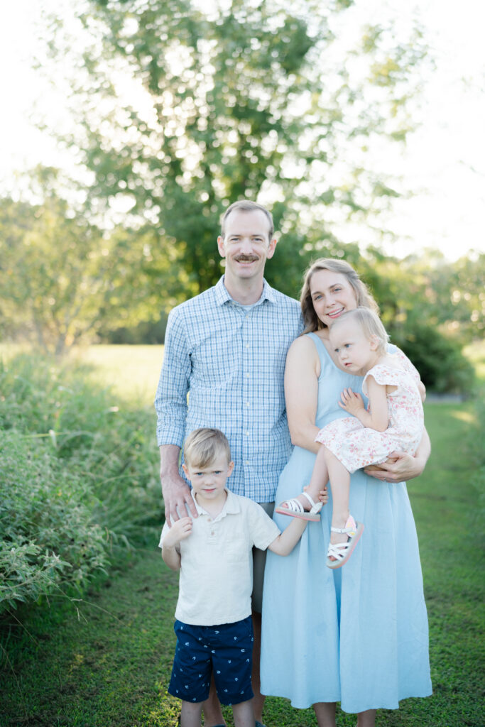 Family of four smiling together outdoors during Nashville summer mini sessions
