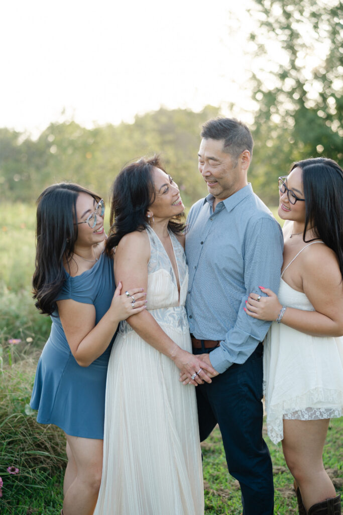 Parents and their two daughters sharing a candid moment together during a summer family photography session