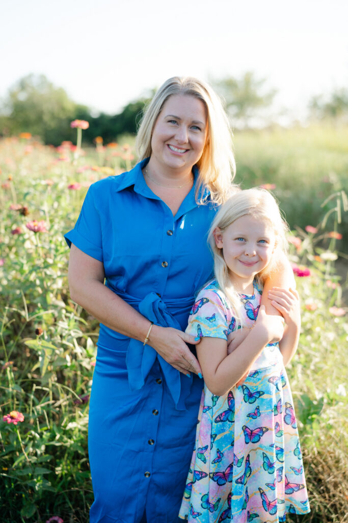 Mother and daughter smiling together among colorful summer flowers during a family photo session