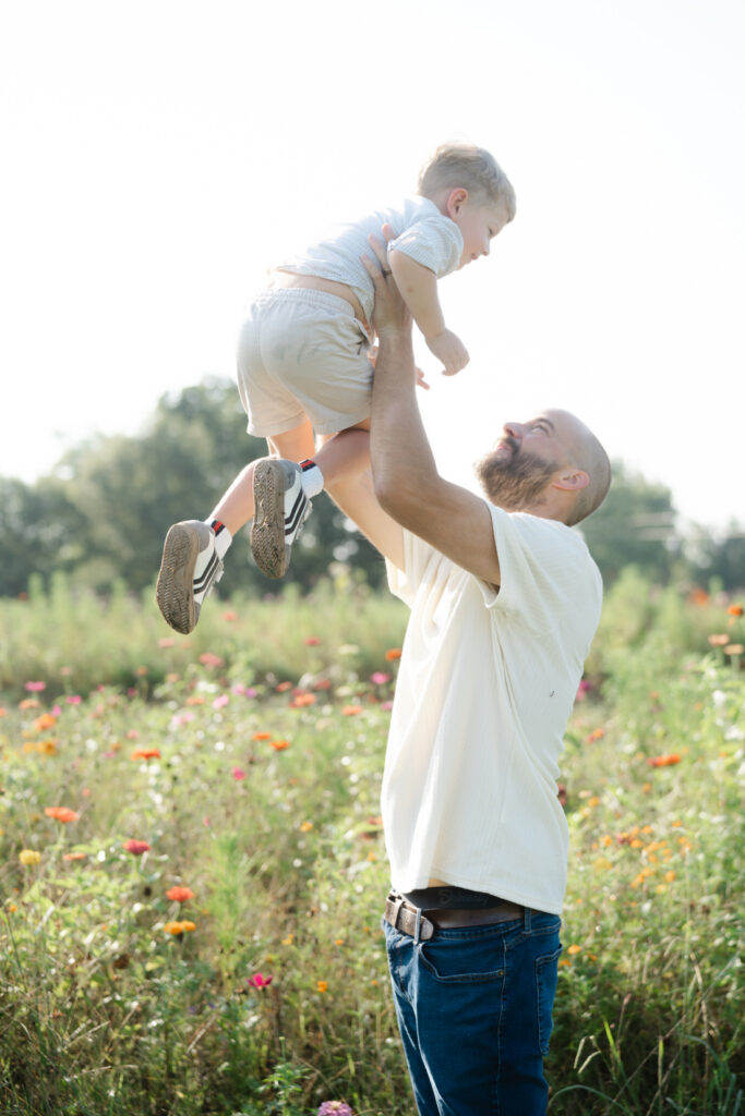 Dad lifting his young son into the air during Nashville summer mini sessions at Perry Family Farm