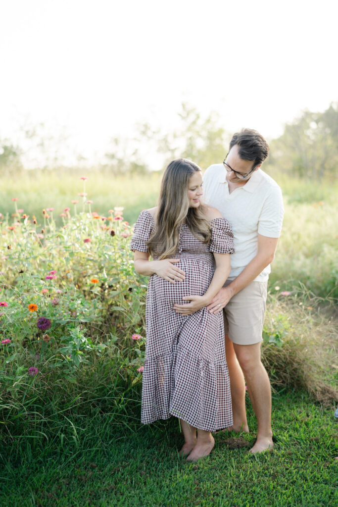Expecting parents standing together among colorful flowers during Nashville summer mini sessions